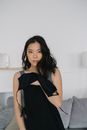 Woman in Black Sleeveless Dress Sitting on Bed