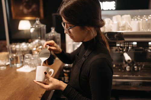 A Woman Pouring Milk in a Cup