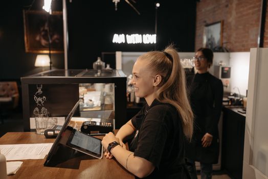 Barista smiling and serving customers at a cozy café counter with warm lighting and modern decor.