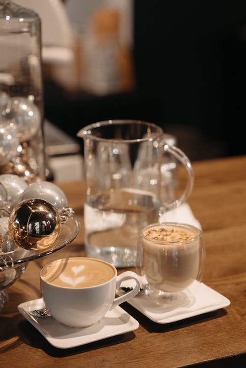 A Ceramic Cup with Coffee Near the Clear Glass on a Wooden Table