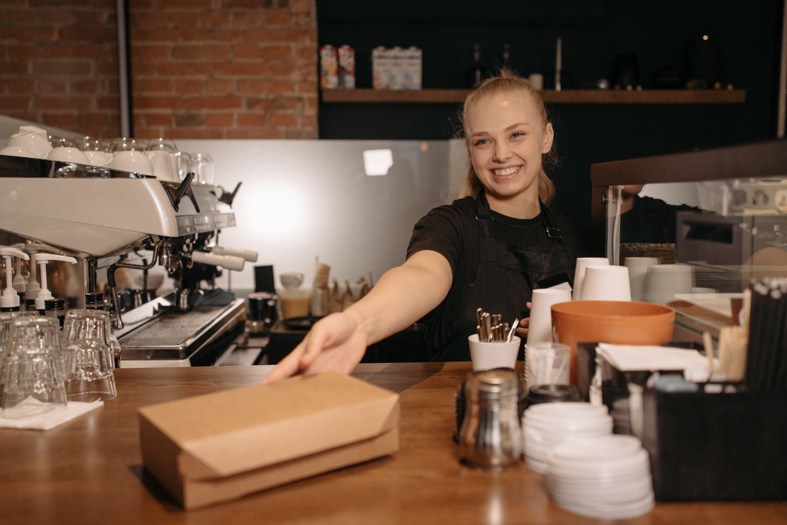 Mujer trabajando en una cafetería con un entorno cálido y acogedor.