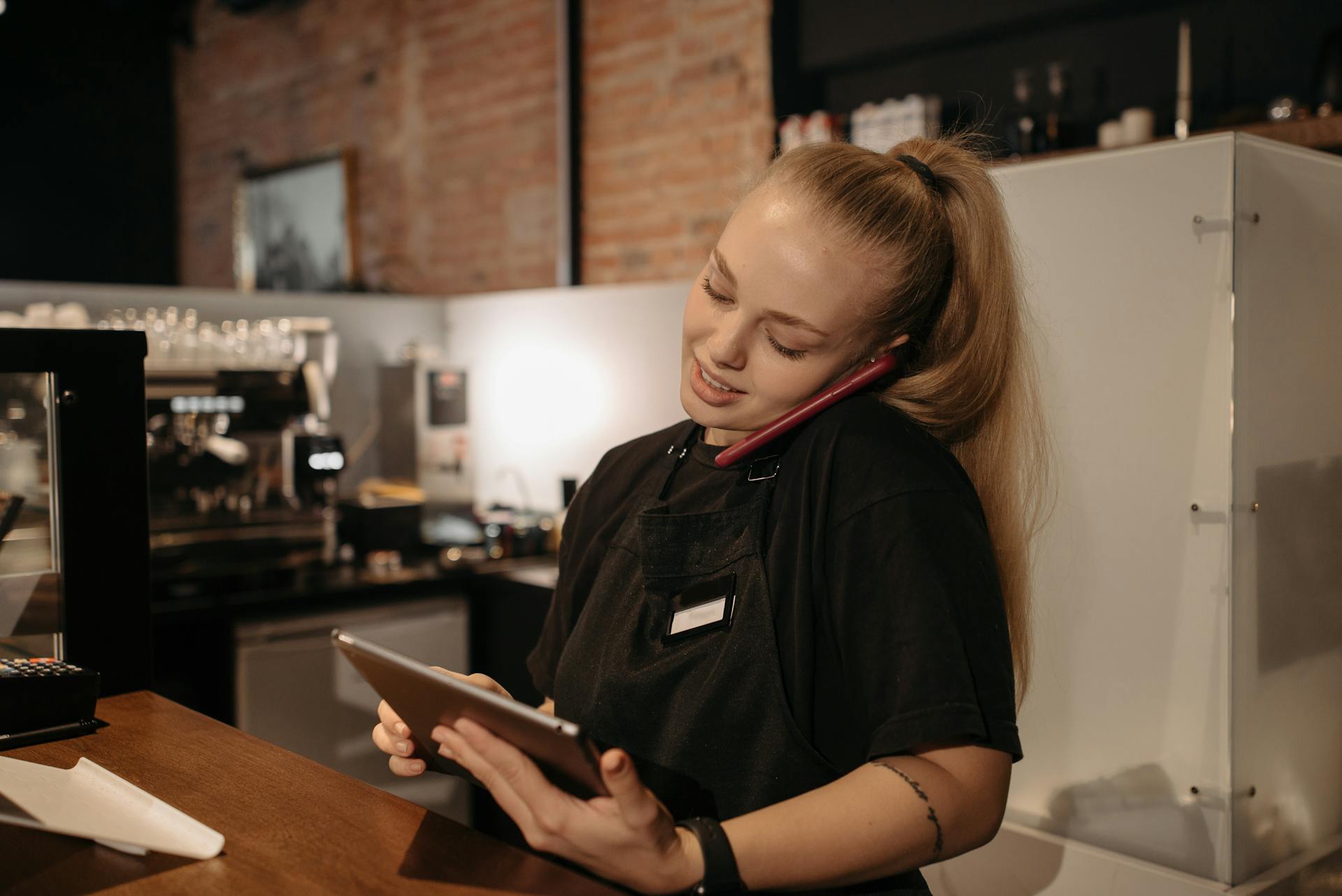 Woman in Black Crew Neck Shirt Taking Online Order Using Smartphone