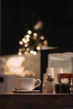 Warm cafe interior with a focus on a cup and saucer on a wooden table.
