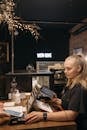 A Woman in Black Shirt Holding a Payment Terminal and a Tablet while on the Counter