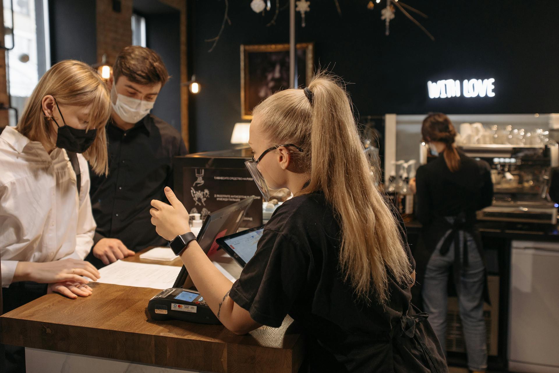 Barista attending to customers in a café using contactless payment during pandemic.