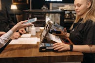 A Woman in Black Shirt Using a Payment Terminal at the Counter