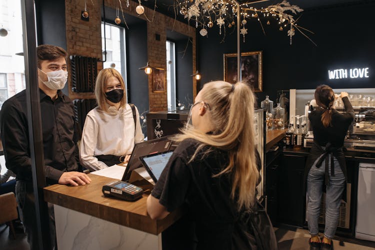 A Couple Wearing Face Masks While Ordering At The Counter