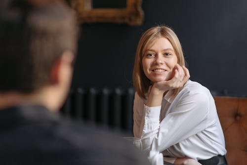 A Beautiful Woman in White Long Sleeves Smiling with Her Hand on Her Chin