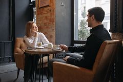 A couple enjoying coffee and conversation in a cozy café setting by the window.