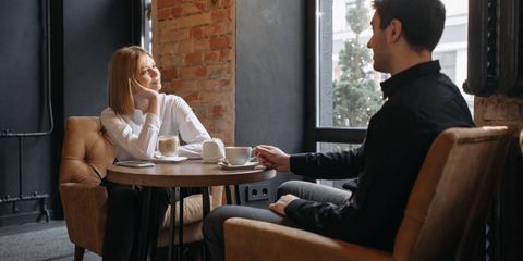 A couple enjoying coffee and conversation in a cozy café setting by the window.