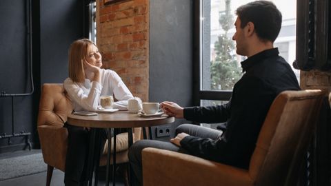 A couple enjoying coffee and conversation in a cozy café setting by the window.