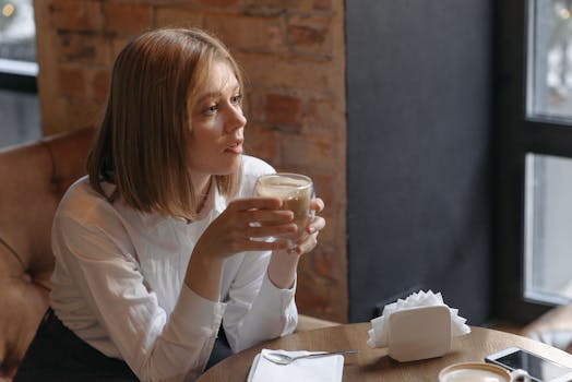 A woman savors a cup of coffee in a warm café setting, capturing a moment of relaxation and leisure.
