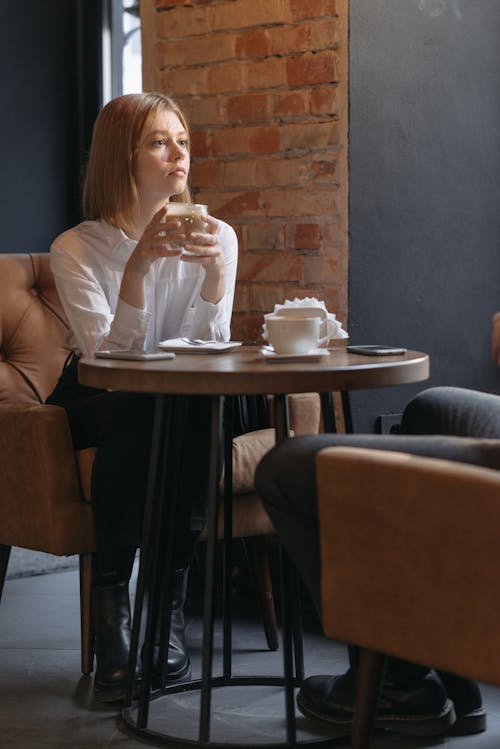 Woman Sitting on Sofa Chair While Holding a Drink