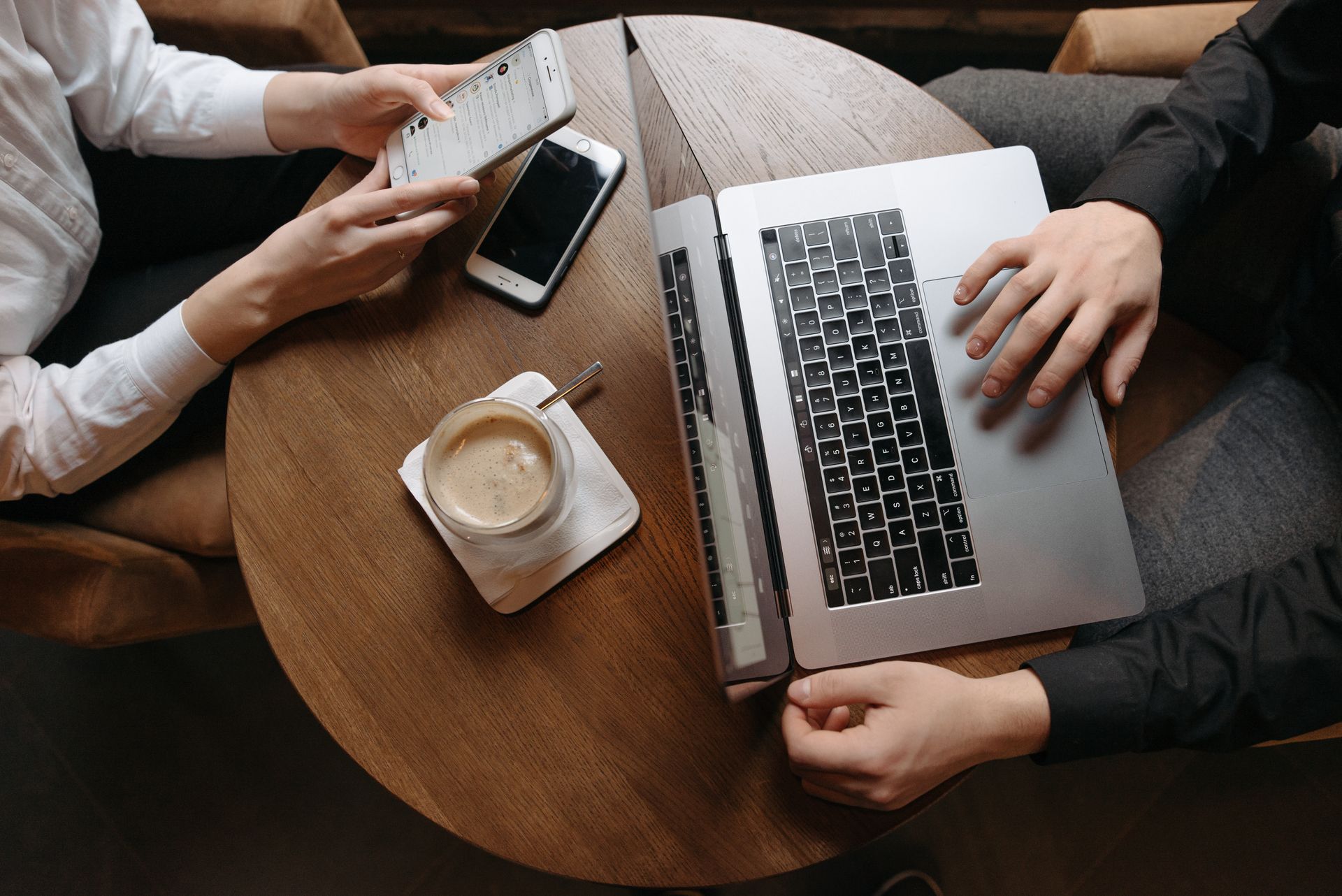 Overhead view of professionals using technology devices at a café table.
