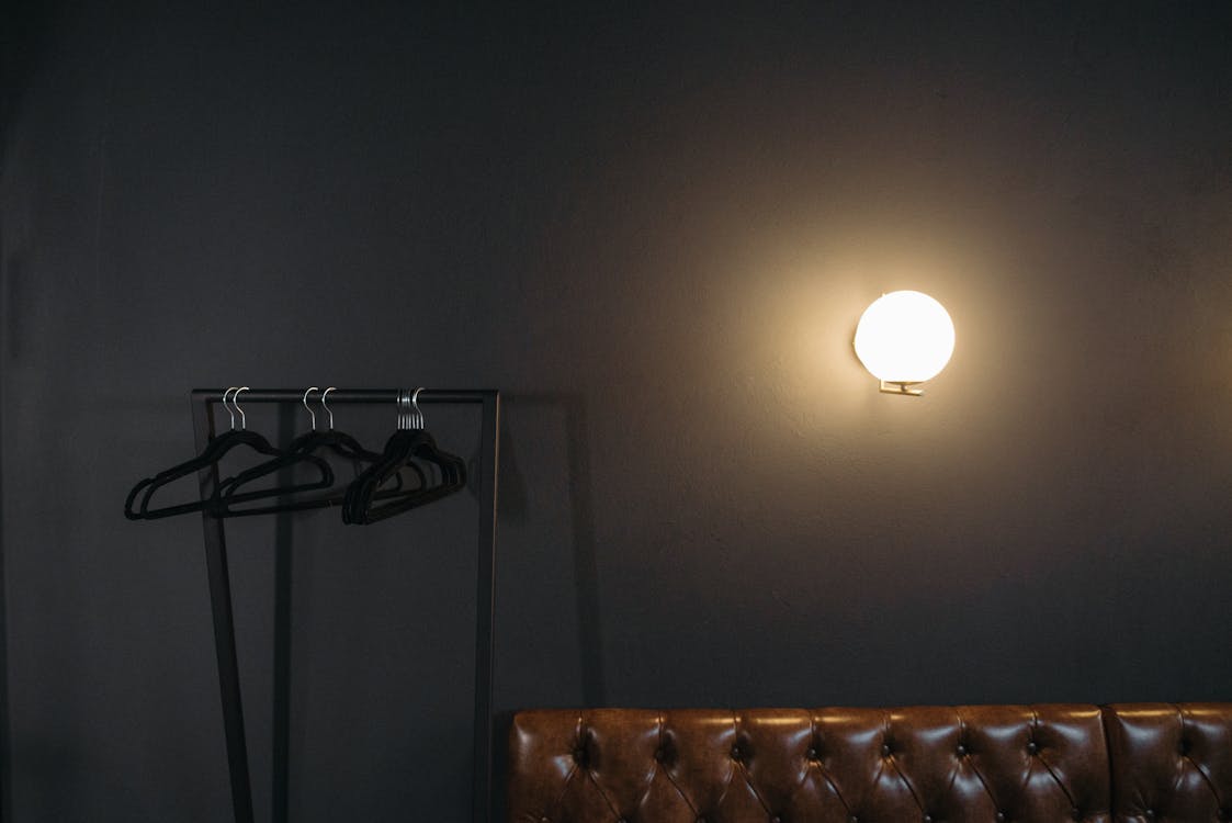 A Light on Gray Wall Near Black Hangers Hanging on Rack