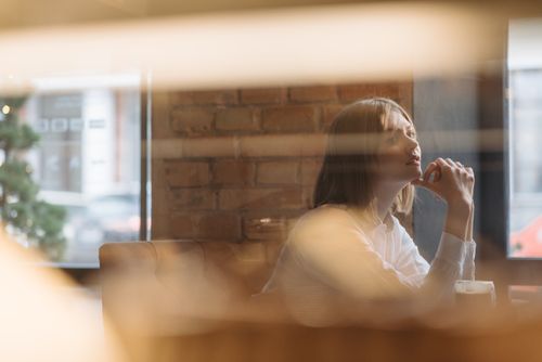 Free Woman in white shirt gazing thoughtfully in urban cafe with exposed brick interior. Stock Photo