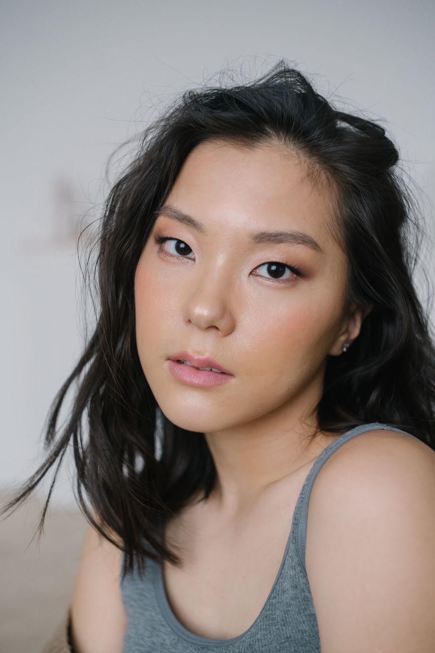 Elegant close-up portrait of a woman with natural makeup and black hair indoors.