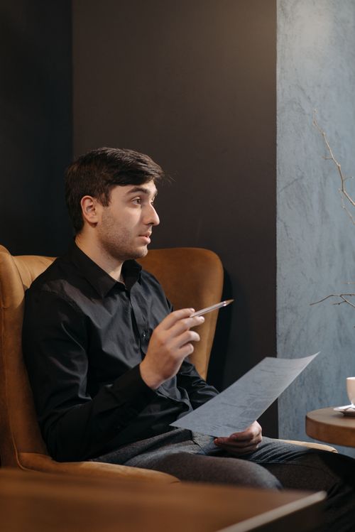 Free A man in a café holding a document, appearing engaged in conversation. Stock Photo