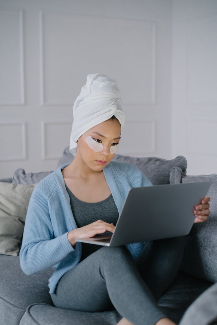 Woman Sitting On Sofa While Using A Laptop