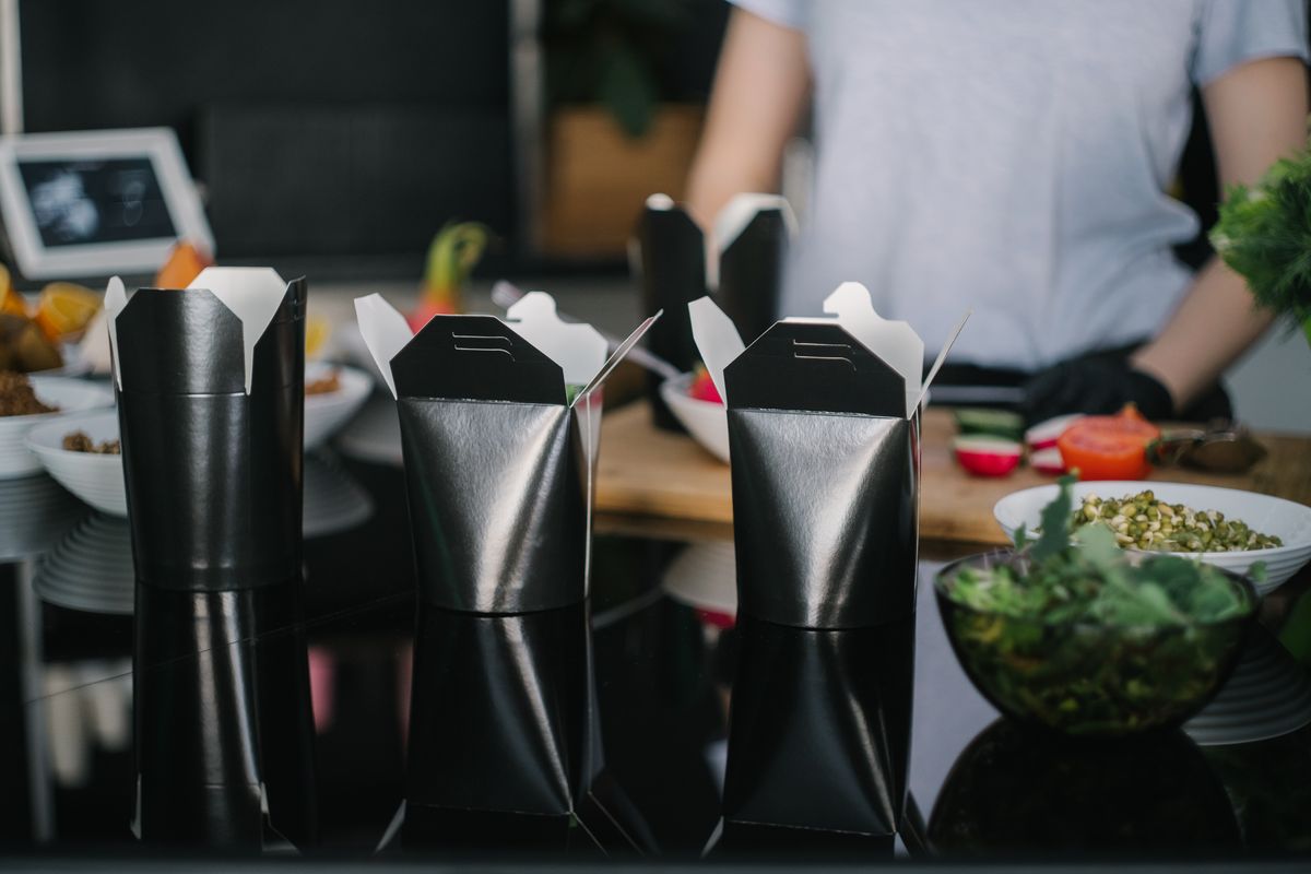 Black takeaway boxes filled and lined up on a counter