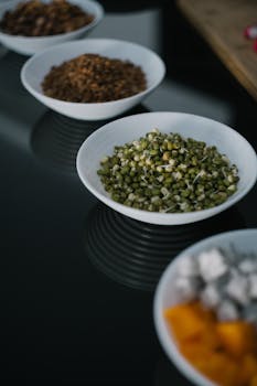 A variety of food bowls featuring mung beans, displayed on a reflective surface.