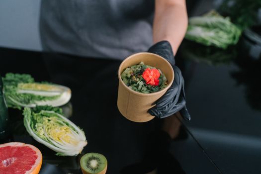 A hand holding a salad bowl with fresh vegetables and a colorful garnish, emphasizing healthy eating.