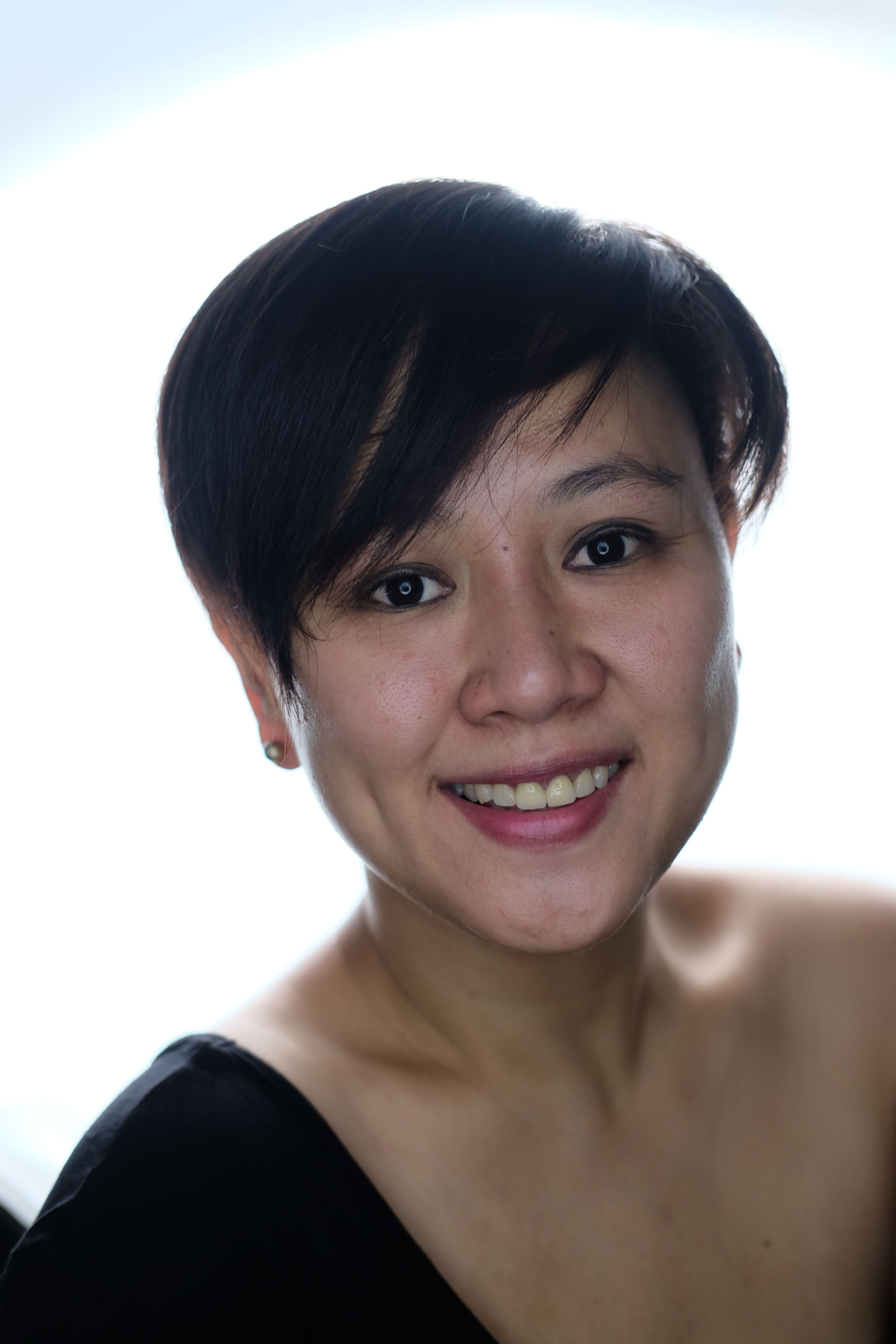 Close-up portrait of a smiling woman with short hair against a bright background.