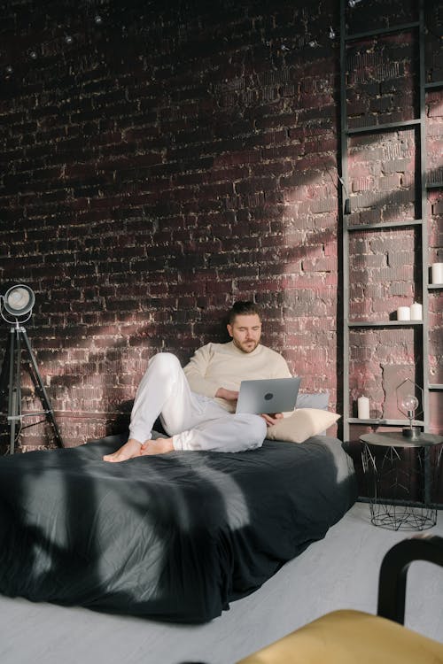 Free A Man Using a Laptop while Lying on the Bed Stock Photo