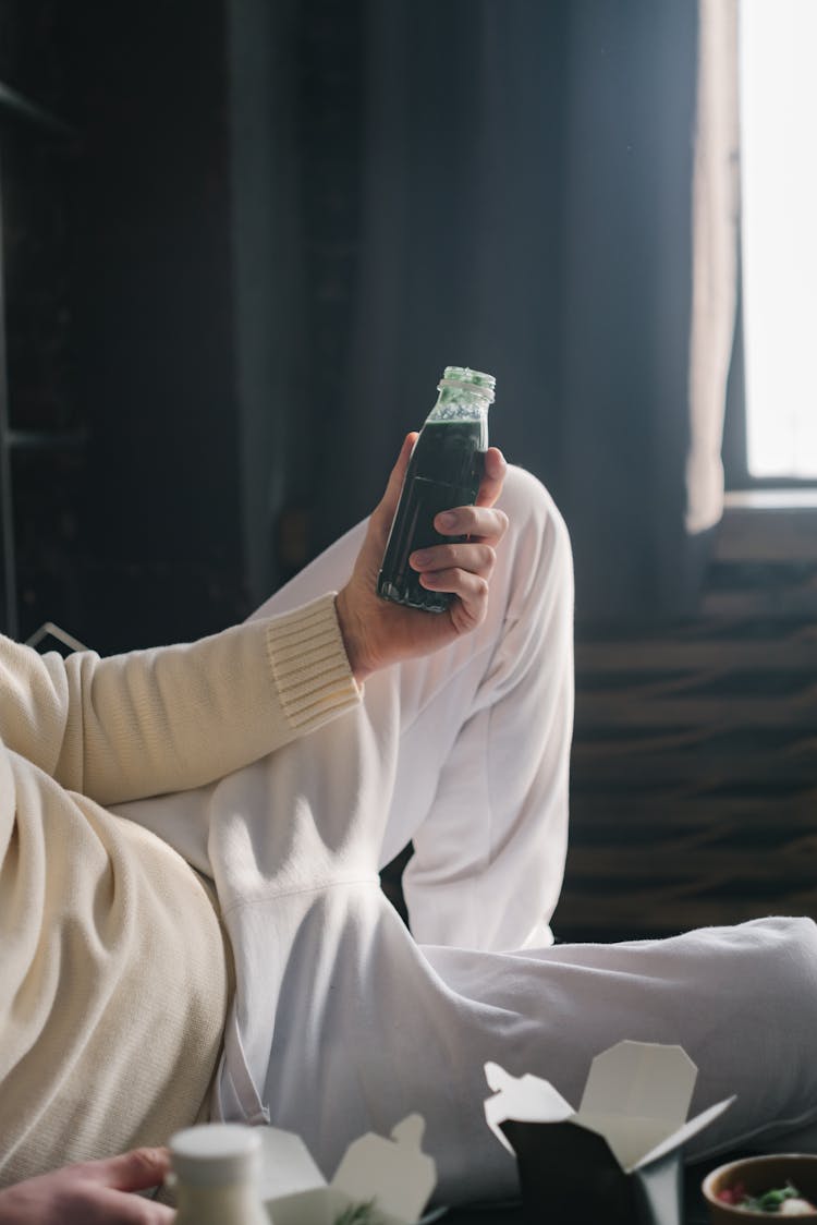 A Person Holding A Glass Bottle