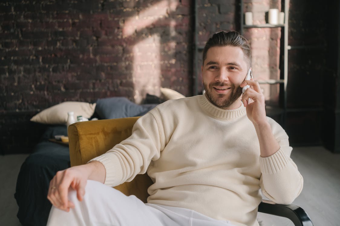 Free Man in White Sweater Sitting on Brown Chair Stock Photo