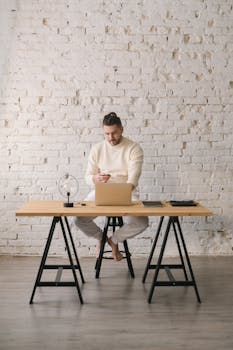Young man working remotely on laptop in stylish home office setting.