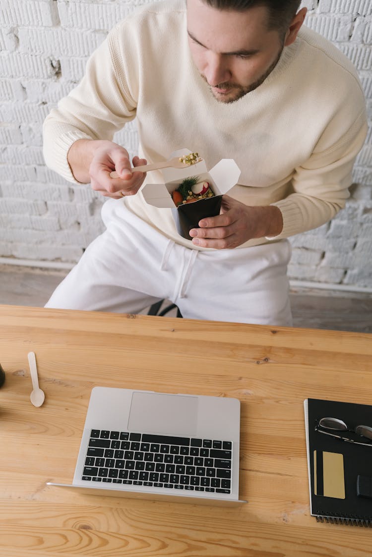 A Man Eating A Healthy Takeaway Lunch At His Workspace