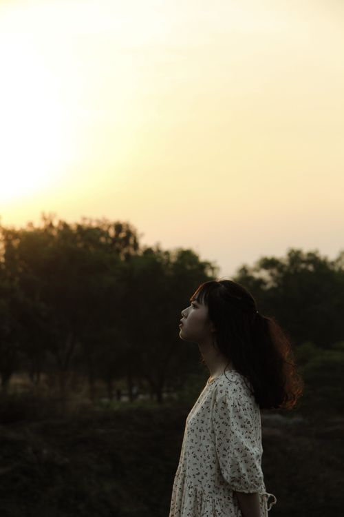 Free A young woman gazes upward during a serene sunset in Ho Chi Minh City. Stock Photo