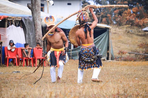 Men in Ethnic Costume Dancing on Brown Field