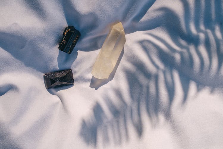 Crystals And Shadow Of A Plant On A White Fabric