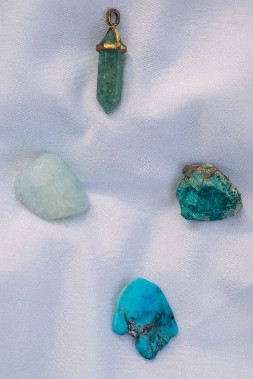 Free A close-up view of assorted gemstones and a pendant on a smooth fabric surface. Stock Photo
