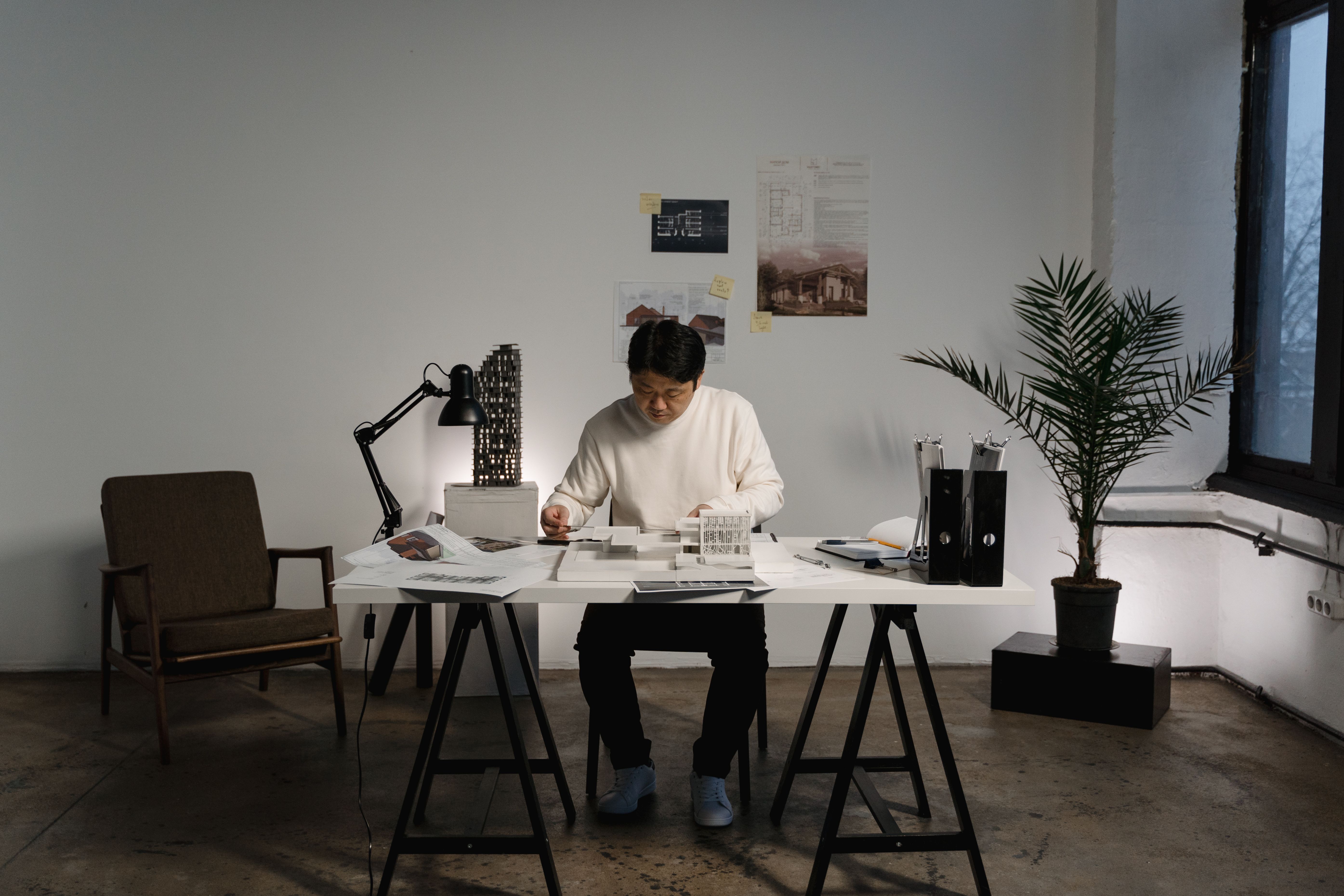 Architectural workspace with a man focused on a project amidst modern indoor decor.