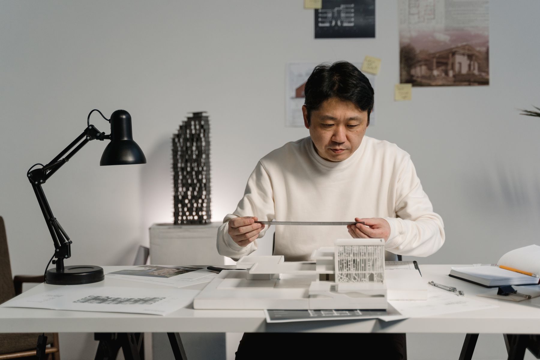 Designer measuring a model beside project drawings
