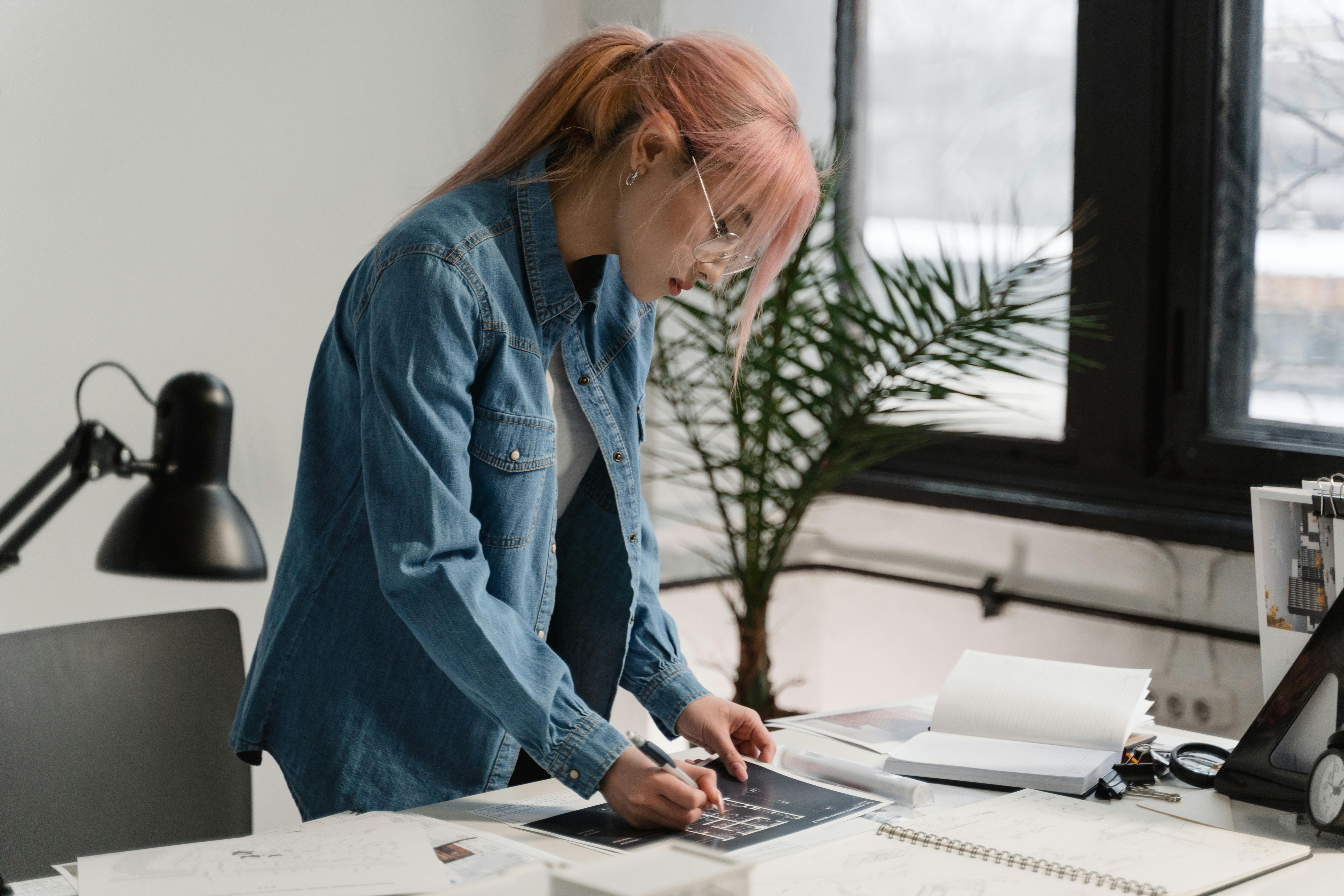 A young woman working on design plans in a creative office setting.