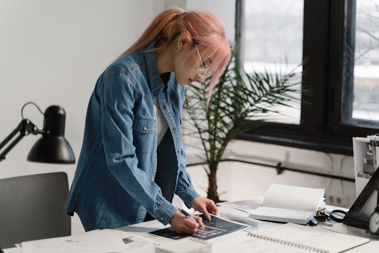 A Woman In Denim Jacket Writing On Paper