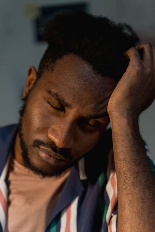 Free Close-up portrait of a tired man with closed eyes, reflecting exhaustion. Ideal for themes of fatigue and rest. Stock Photo