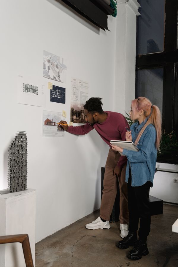 Two colleagues reviewing sketches on a studio wall — photo by Tima Miroshnichenko on Pexels