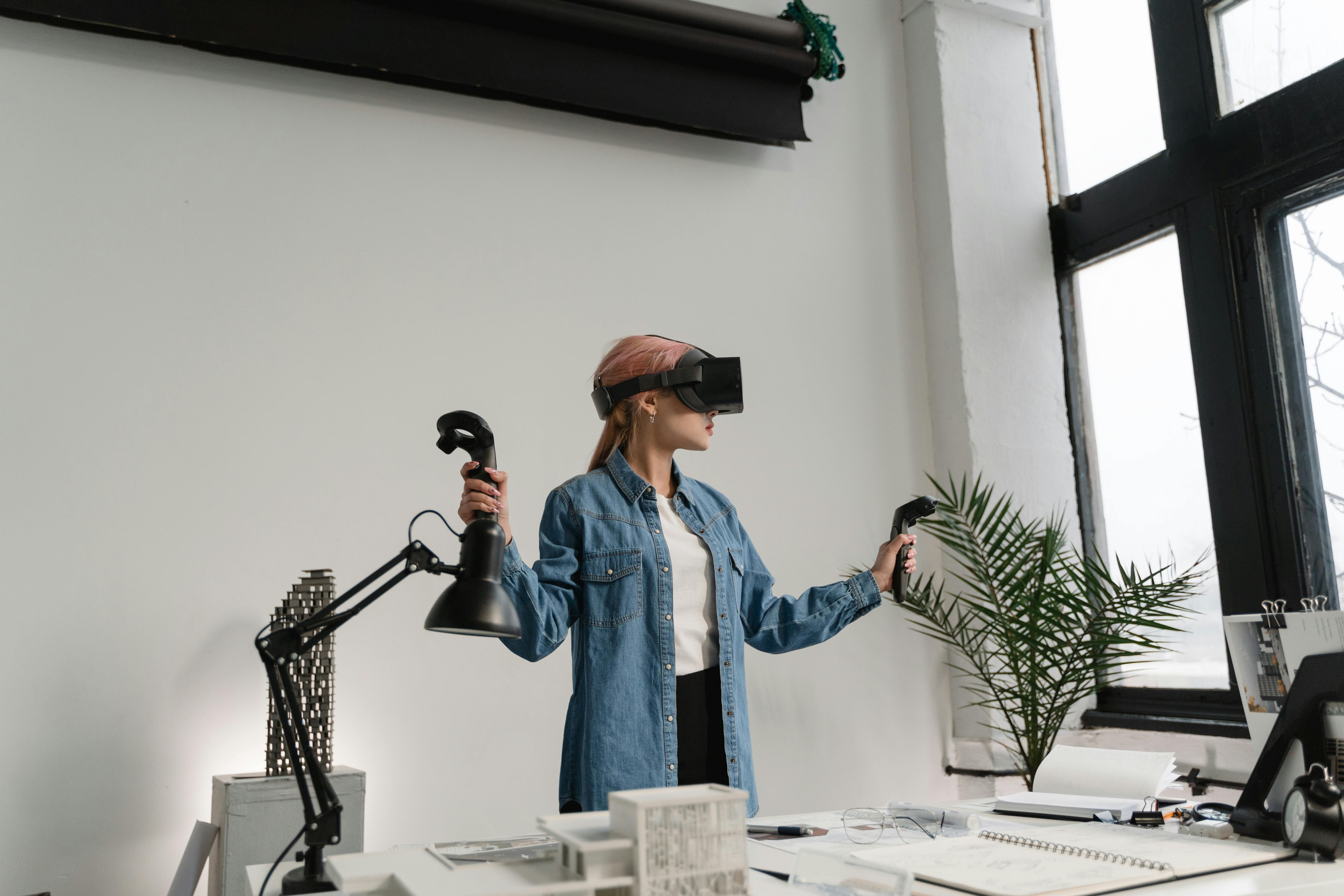 a woman in denim jacket wearing vr headset while holding black controllers