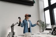 A Woman in Denim Jacket Wearing VR Headset while Holding Black Controllers