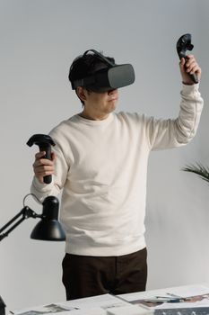 Adult man using VR headset and controllers in a modern office setting.