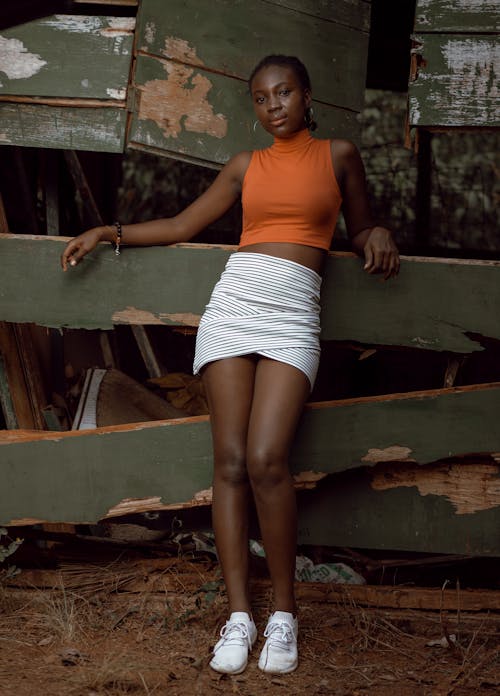 Stylish young black female model leaning on wooden fence and looking at camera