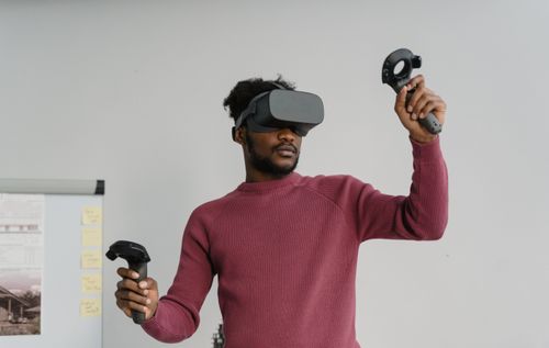Free A man uses a VR headset and controllers for an immersive gaming experience indoors. Stock Photo