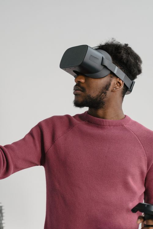 Free Young man immersed in virtual reality using a headset and controller in a modern setting. Stock Photo
