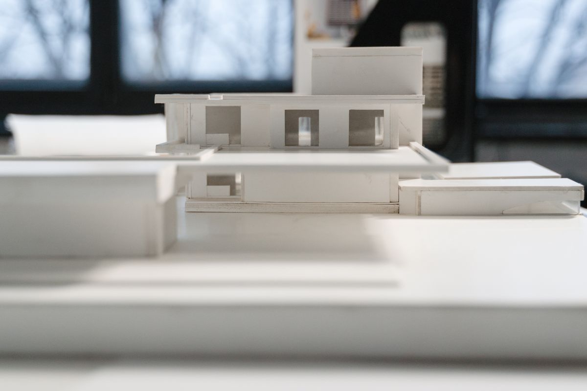 Architect at a studio table with a physical model in natural light