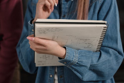Free Person in Denim Jacket Holding a Sketch Pad Stock Photo